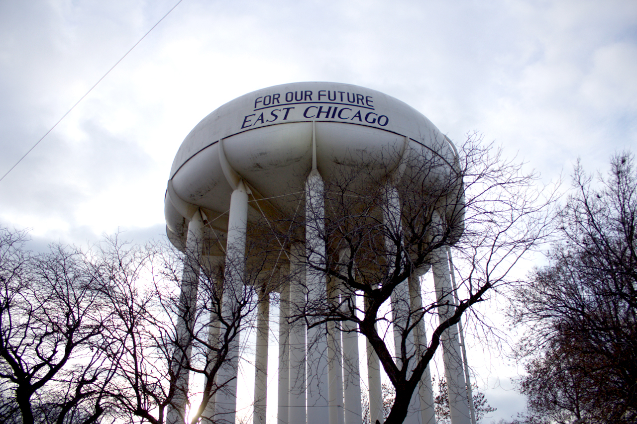 The East Chicago water tower looms over the U.S.S. Lead Superfund site. On the side of the tower is writte, 'For our future: East Chicago.'